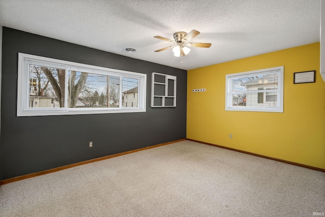 unfurnished room with a textured ceiling, ceiling fan, carpet flooring, visible vents, and baseboards