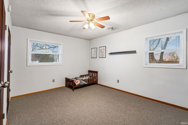 unfurnished bedroom with a textured ceiling, carpet flooring, visible vents, and baseboards