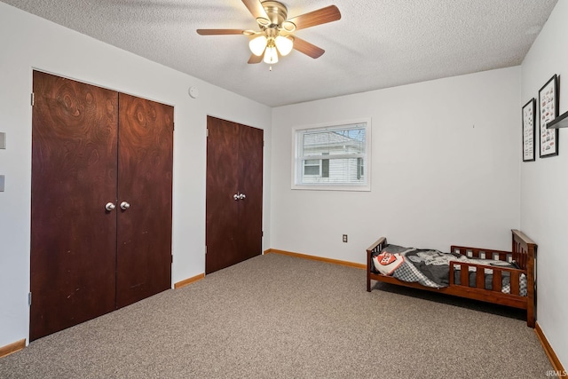 bedroom featuring carpet, a textured ceiling, baseboards, and two closets