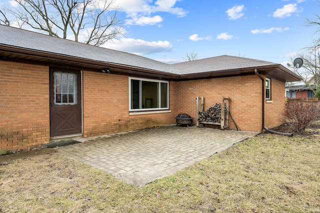 rear view of house with brick siding, a patio, and a lawn