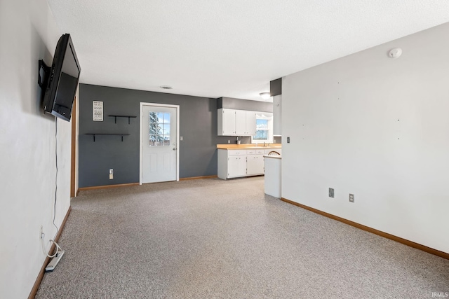 unfurnished living room with baseboards and a textured ceiling