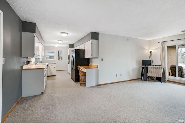 kitchen with baseboards, white cabinets, and freestanding refrigerator