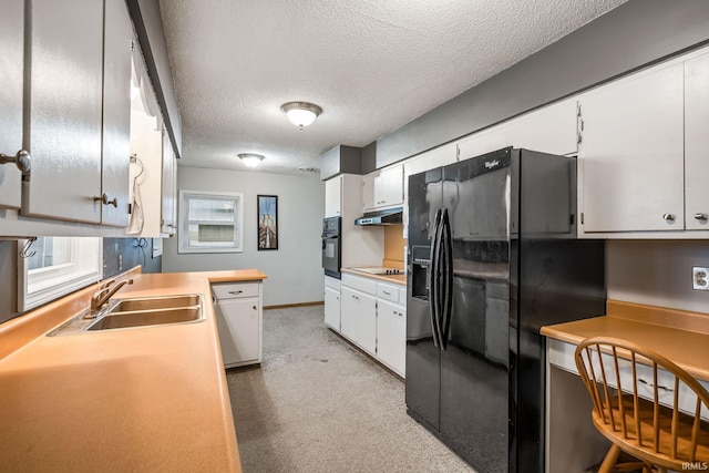 kitchen featuring white cabinets, under cabinet range hood, light countertops, black appliances, and a sink