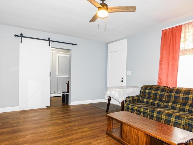 sitting room featuring a barn door, wood finished floors, a ceiling fan, baseboards, and baseboard heating