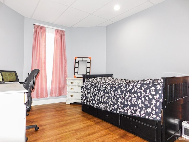 bedroom with wood finished floors, a paneled ceiling, and baseboards