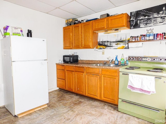 kitchen with white appliances, a drop ceiling, a sink, and brown cabinetry