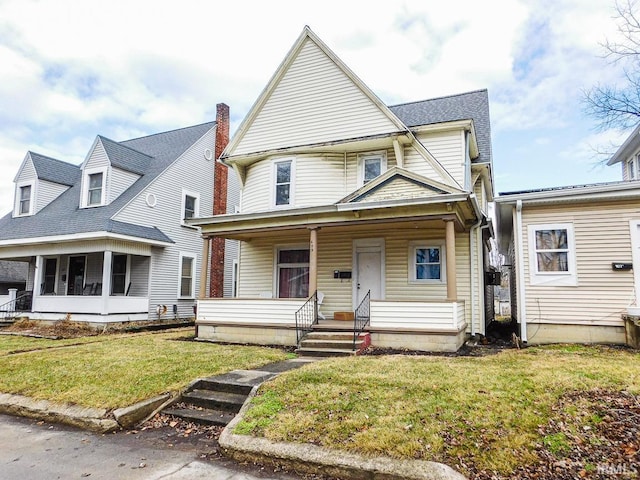 view of front of house featuring a shingled roof, a front yard, and covered porch