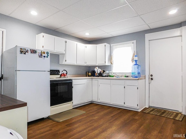 kitchen with dark wood-style floors, freestanding refrigerator, white cabinetry, and range with electric stovetop