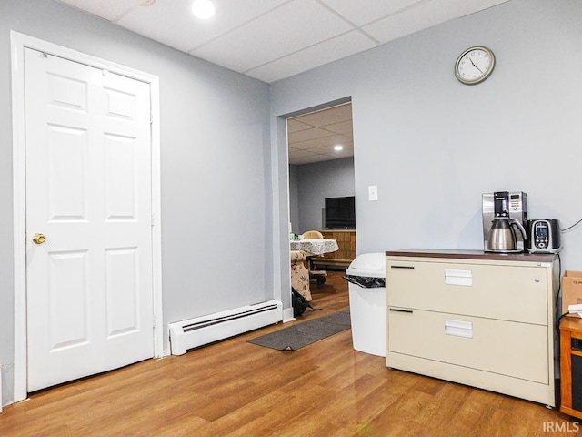 kitchen with baseboard heating, a drop ceiling, and wood finished floors