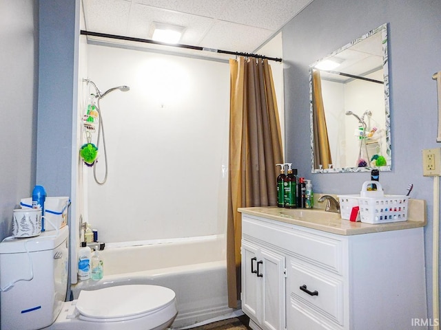 full bath featuring toilet, shower / bath combo with shower curtain, a paneled ceiling, and vanity