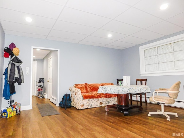 interior space with a paneled ceiling, baseboards, baseboard heating, and wood finished floors