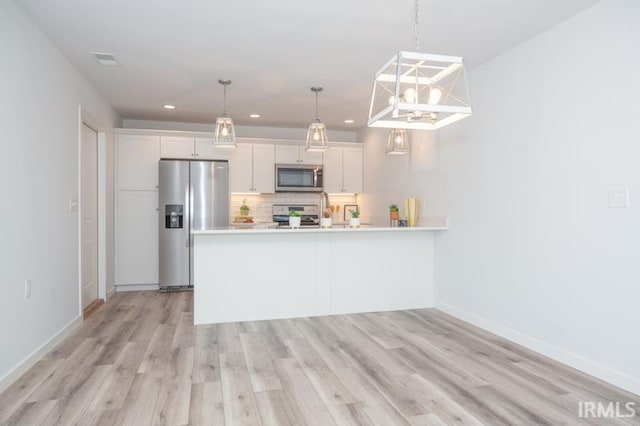 kitchen featuring light wood-style flooring, stainless steel appliances, white cabinetry, light countertops, and tasteful backsplash