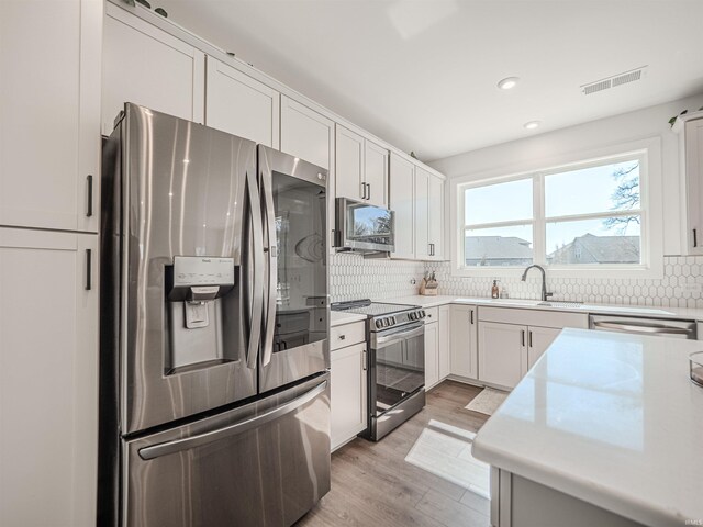 kitchen with backsplash, visible vents, stainless steel appliances, and a sink