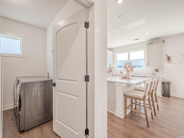 washroom with washer / clothes dryer, visible vents, light wood-style floors, laundry area, and baseboards