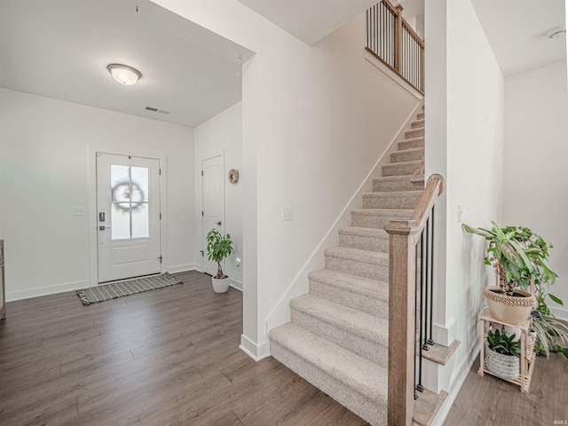 entryway with stairs, visible vents, baseboards, and wood finished floors