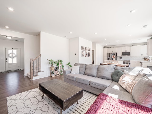 living room with recessed lighting, wood finished floors, visible vents, and stairs