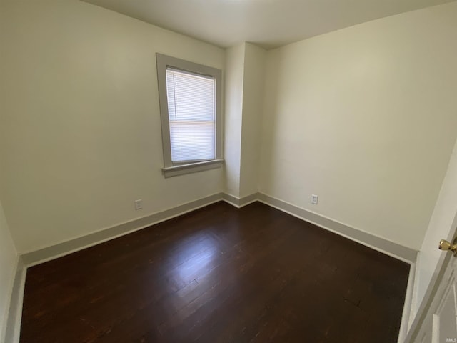 unfurnished room with dark wood-type flooring and baseboards