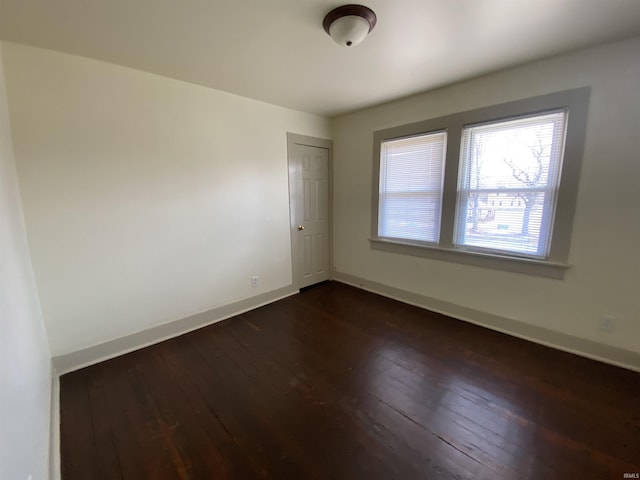 unfurnished room featuring dark wood-type flooring and baseboards