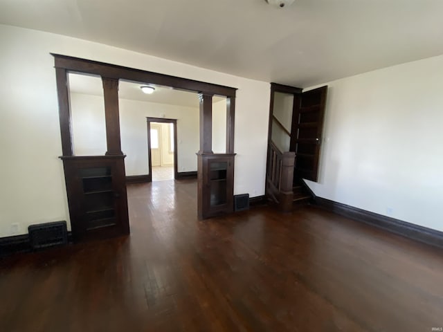 unfurnished room with dark wood-style floors, visible vents, stairs, and baseboards