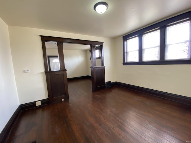 spare room with dark wood-type flooring and baseboards