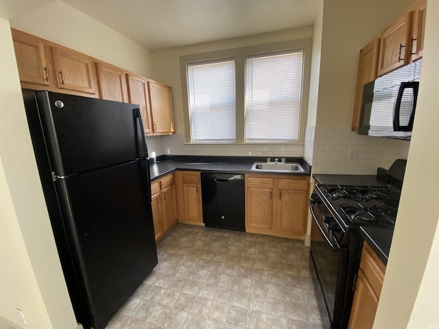 kitchen featuring dark countertops, black appliances, tasteful backsplash, and a sink