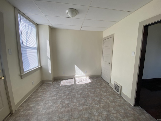 unfurnished room featuring baseboards, visible vents, and a drop ceiling