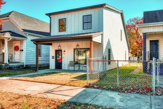 view of front of property with covered porch, fence, a front lawn, and board and batten siding