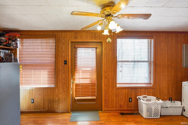 doorway to outside with wood walls, wood finished floors, and electric panel