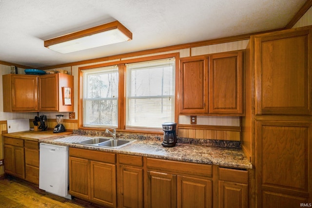 kitchen with brown cabinetry, white dishwasher, and a sink