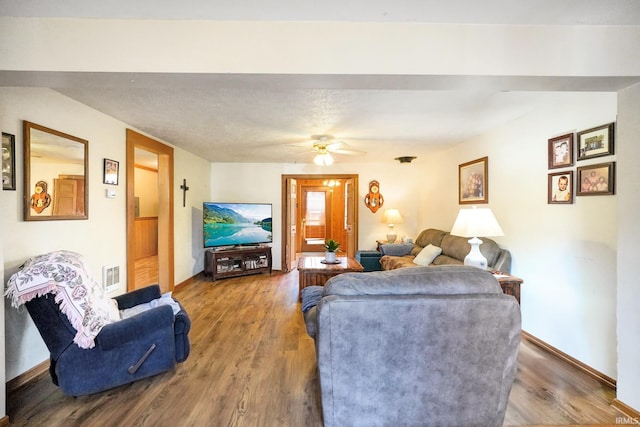 living area featuring a ceiling fan, visible vents, baseboards, and wood finished floors