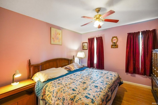 bedroom with a ceiling fan, baseboards, and wood finished floors