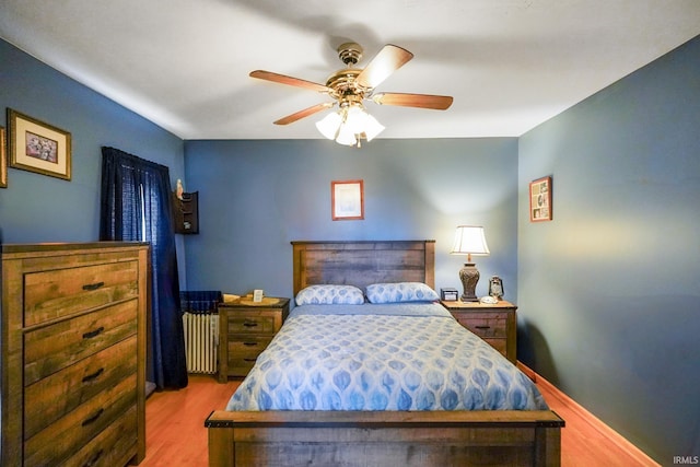 bedroom featuring ceiling fan, radiator heating unit, and wood finished floors