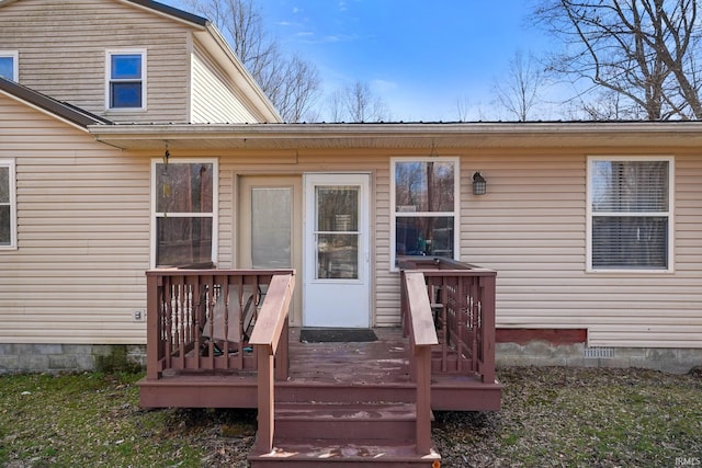 view of exterior entry with crawl space and a wooden deck