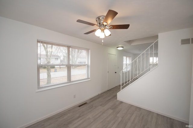 interior space with light wood-type flooring, visible vents, ceiling fan, and baseboards