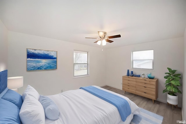 bedroom featuring a ceiling fan, baseboards, and light wood finished floors