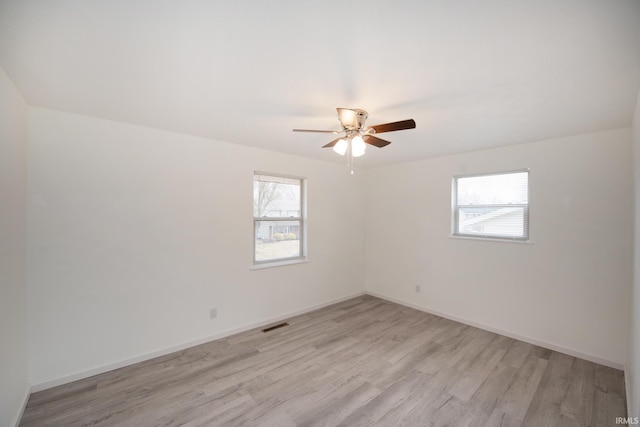 empty room featuring a ceiling fan, baseboards, visible vents, and light wood finished floors