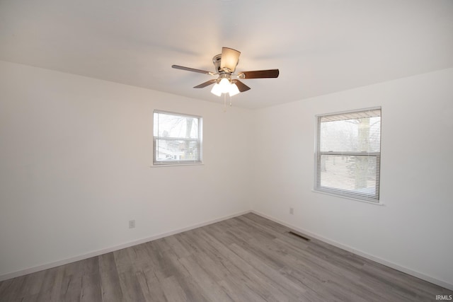 spare room featuring visible vents, ceiling fan, baseboards, and wood finished floors