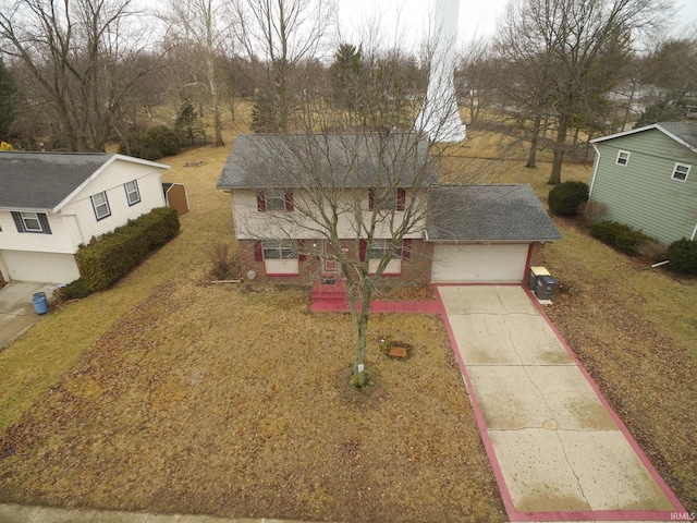 traditional-style house featuring a shingled roof, concrete driveway, brick siding, and a front lawn