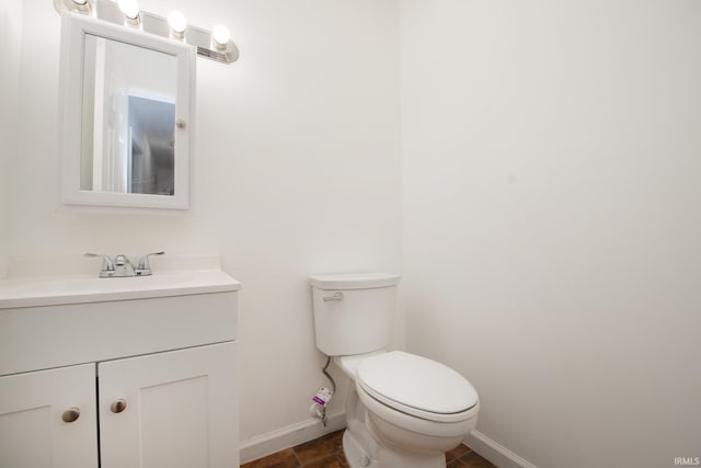 bathroom with baseboards, vanity, and toilet