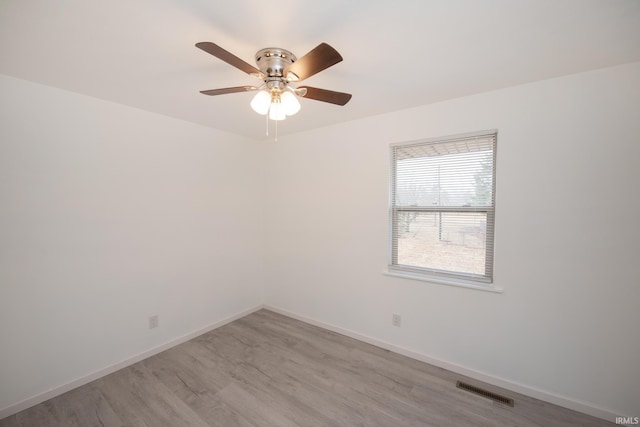 empty room with a ceiling fan, light wood-type flooring, visible vents, and baseboards