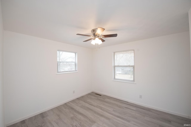 empty room with baseboards, ceiling fan, visible vents, and light wood-style floors