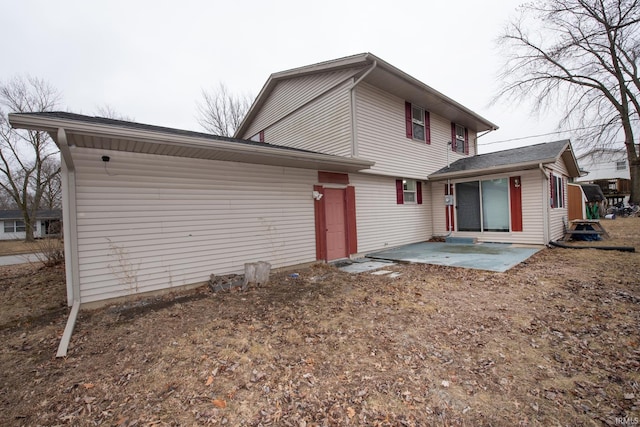 back of property with entry steps and a patio