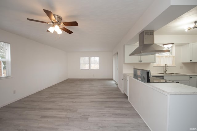 kitchen with baseboards, a sink, light wood-style flooring, and island range hood