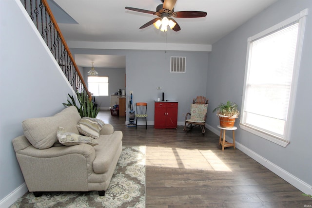 living area with baseboards, stairs, visible vents, and wood finished floors