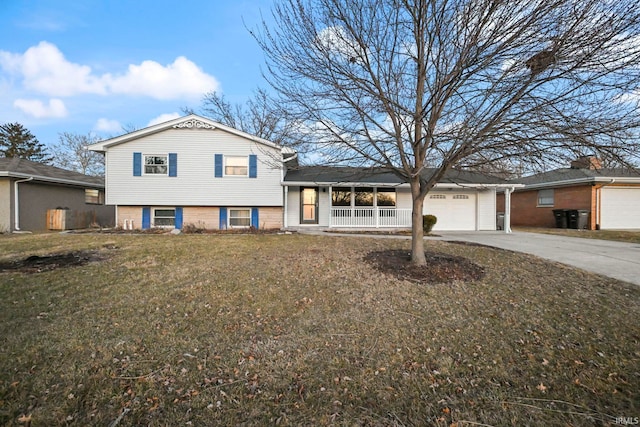 tri-level home with a porch, concrete driveway, a front lawn, and an attached garage