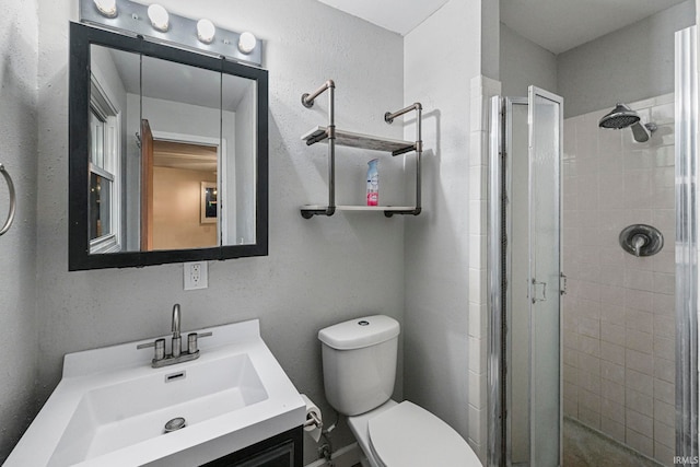 full bathroom with a textured wall, a shower stall, toilet, and vanity