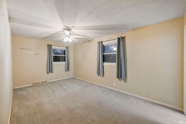 spare room featuring ceiling fan, visible vents, baseboards, a wealth of natural light, and carpet