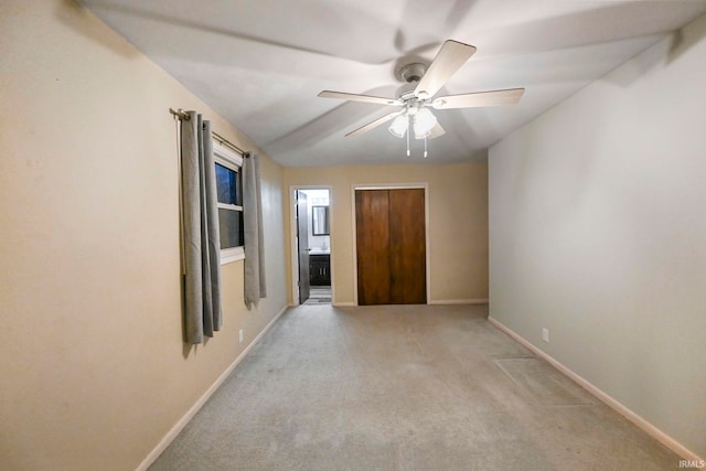 unfurnished bedroom with light carpet, a closet, baseboards, and connected bathroom