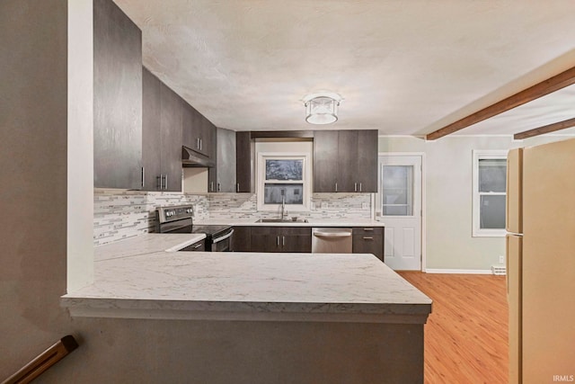 kitchen featuring dark brown cabinetry, under cabinet range hood, stainless steel appliances, a peninsula, and a sink