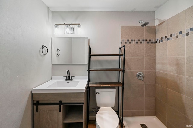 bathroom with vanity, a tile shower, and toilet